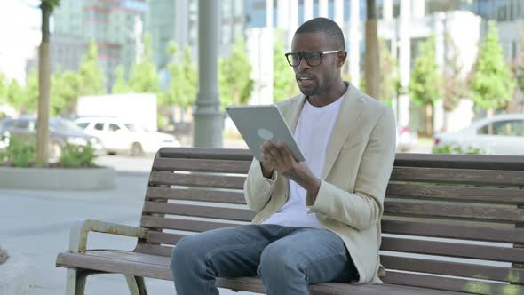 Upset African Man Reacting to Loss on Tablet While Sitting Outdoor on Bench