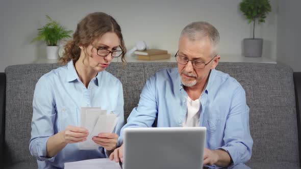 An Agitated Elderly Couple Checks Unpaid Debts on a Laptop and Gets Upset