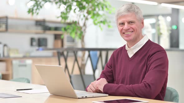 Cheerful Middle Aged Man with Laptop Smiling at the Camera 
