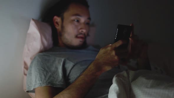 Young Asian men using a smartphone browsing web and scroll through social media feeds.