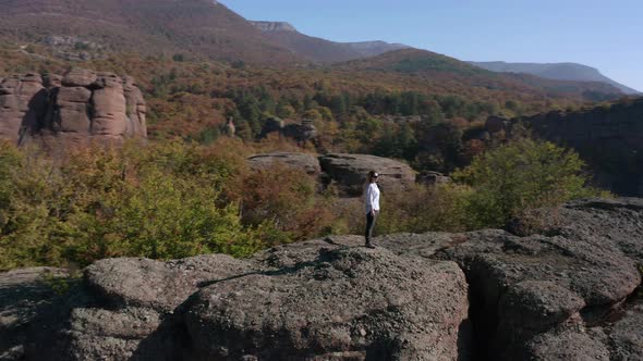 Aerial video with a woman at the edge of stunning rock formation