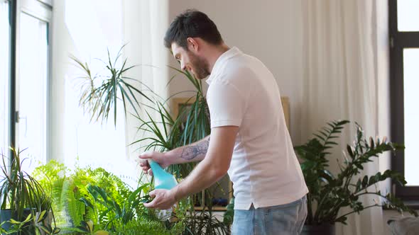 Man Spraying and Cleaning Houseplants at Home