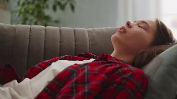 Tired Young Woman in Checkered Shirt Falls Down Onto Sofa