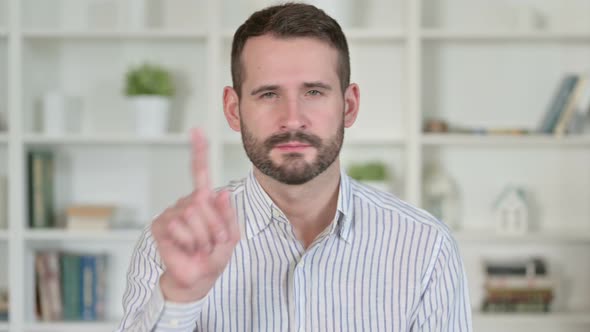 Portrait of Young Man Saying No with Finger Sign