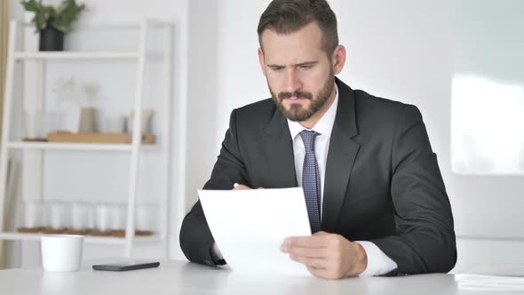 Tense Businessman Reacting to Loss While Reading Documents