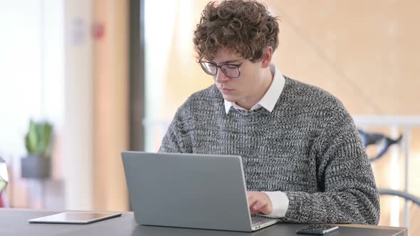 Young Man with Laptop Looking at the Camera