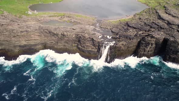 Aerial view of a waterfall near cliff on North Atlantic sea, Faroe island.