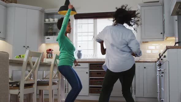 Mixed race lesbian couple and daughter dancing in kitchen