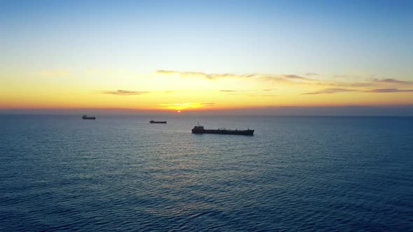 Cargo Ships Off The Coast In Sunrise Or Sunset At Sea