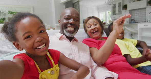 Happy african american grandparents and grandchildren sitting on sofa, having video call