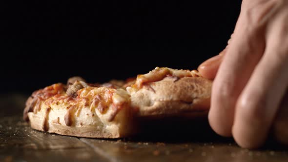 A hand picking up a slice of pizza out of a whole pizza. Slow Motion.