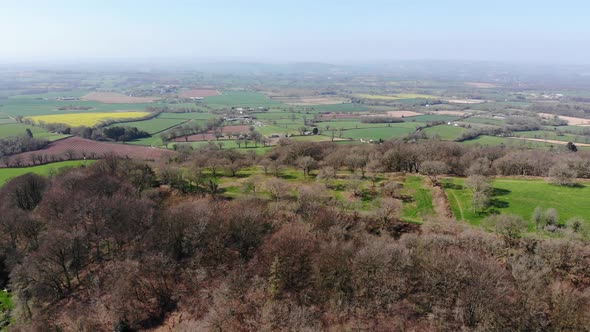 Aerial panning right shot of the Iron age Hill Fort at Hembury Devon England with the East Devon Cou