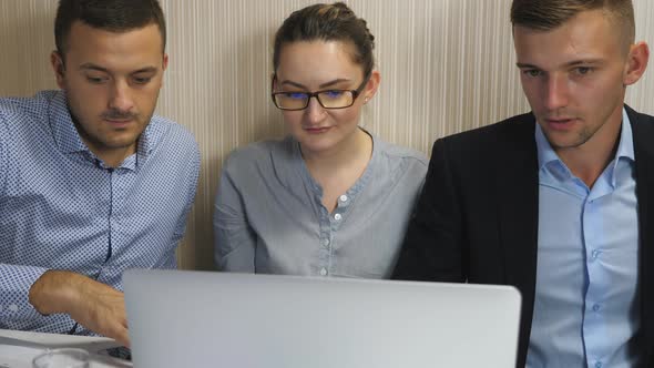 Young Coworkers Examining Financial Reports on Computer at Office
