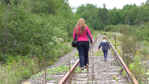 A mother walking with her child on an abandoned railway.