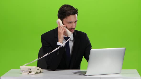 Man Talking on Telephone at His Workplace in the Office