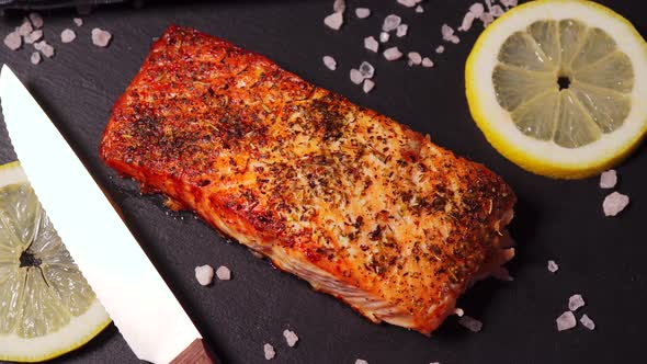 Delicious Baked Golden Salmon on a Black Plate in the Kitchen