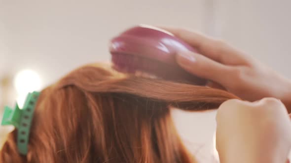 Female Hairdresser Combing Hair to Redhead Girl in Beauty Salon Slow Motion