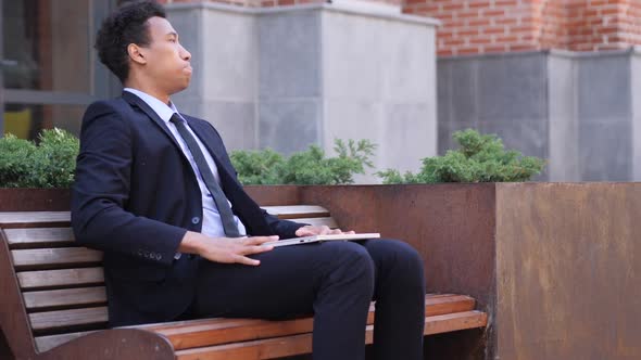 Loss African Businessman Frustrated By Results on Laptop While Sitting on Bench