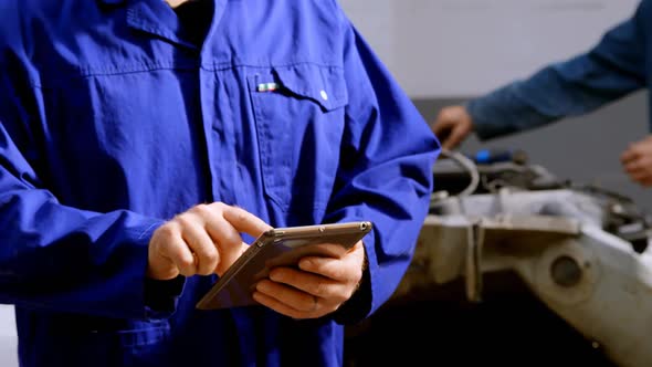 Mechanic using digital tablet at repair garage 4k