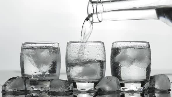 Pouring Up Shot of Vodka From a Bottle Into Glass. White Background