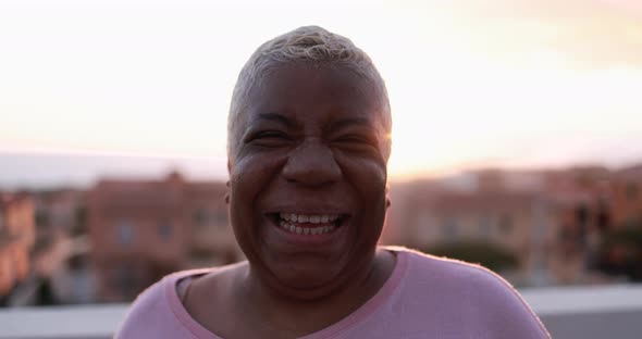 Senior african woman looking and smiling in camera at sunset