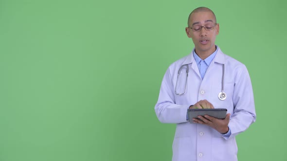 Happy Bald Multi Ethnic Man Doctor Presenting Something with Digital Tablet