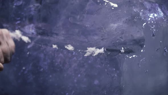 Man is Carving Out Ice to Make a Sculpture Using a Knife