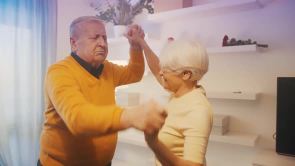 Happy Old Couple Dancing with Disco Lights in Hotel Room