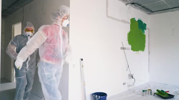 Joyful Couple in Protective Suits Respirators Enters Room