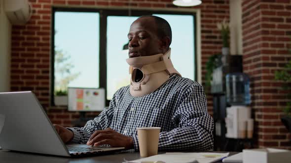 Office Worker in Pain Working with Medical Neck Foam at Desk