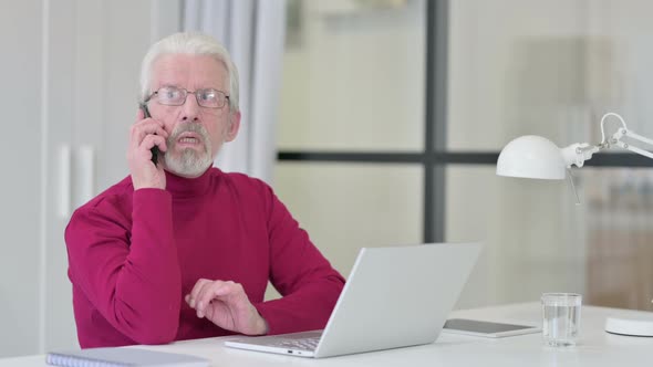 Old Man with Laptop Talking on Smartphone