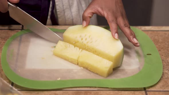 Close up of black hands cutting a yellow fruit into small pieces