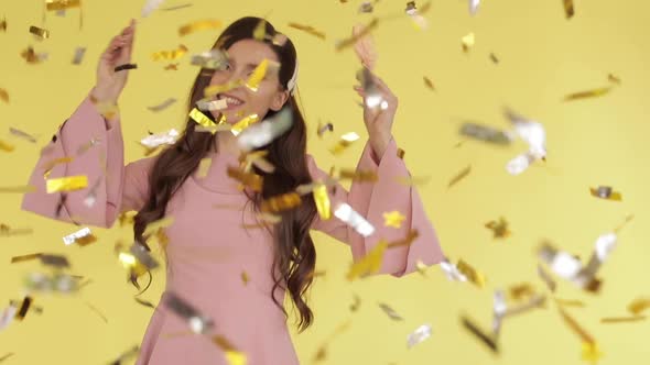 Beautiful Brunette Girl in Pink Dress Dancing with Candies Under Confetti