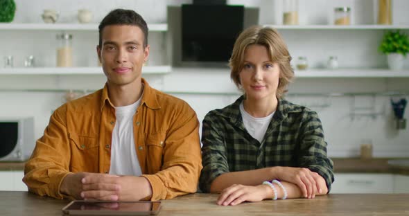 Portrait of Young Mixed Race Couple Sitting at Table in Kitchen