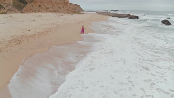 Woman In A Dress Wandering On The Beach