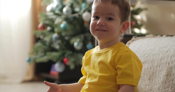 Funny Little Boy Smiling on the Background of Christmas Lights, Cute Baby Looking at the Camera