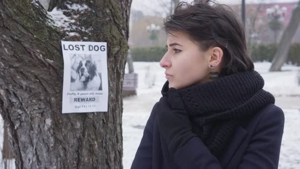 Close-up Portrait of Sad Caucasian Girl Standing on Winter Street and Looking Around. Announcement