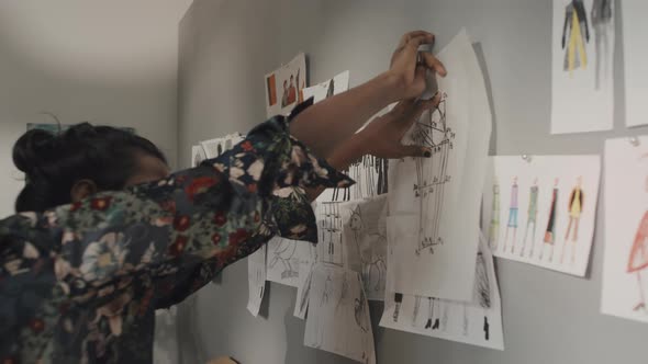 Indian Fashion Designer Attaching Sketch to Wall