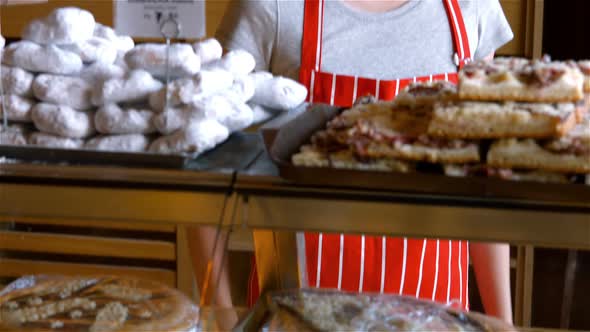 Portrait of female baker holding sweet food in tray