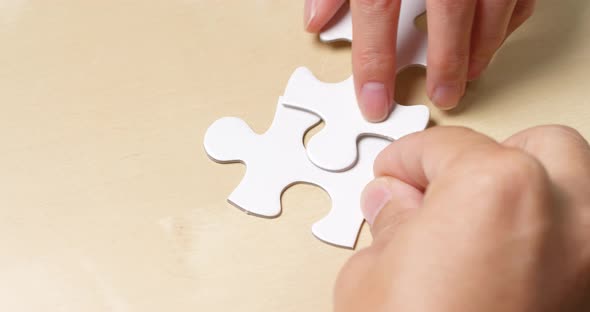 Teamwork completing white puzzle