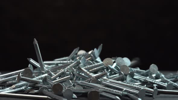 Metal Steel Nails for Construction Work Falling on a Rotating Surface on a Black Background Hobnails