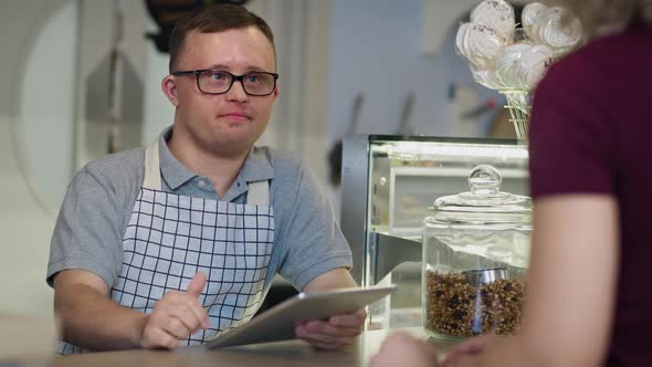 Caucasian man with down syndrome taking order in the cafe using a digital tablet. Shot with RED heli