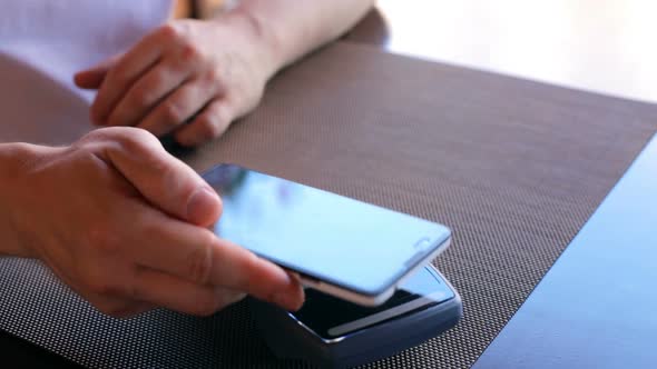 A male customer pays using NFC contactless payment technology on a smartphone.