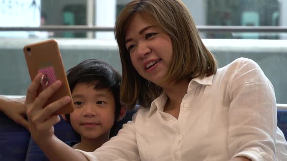 Asian Mother And Her Son Using Mobile Take A Photo Together,They Travels On A Train Slow Motion