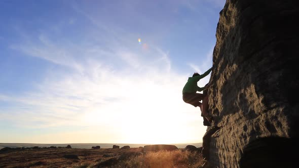 Silhouette of a man climbing boulders while bouldering.