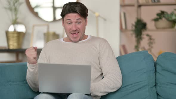 Successful Middle Aged Man Celebrating on Laptop , at Home