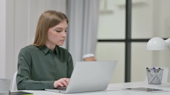 Woman Drinking Coffee While Typing on Laptop 