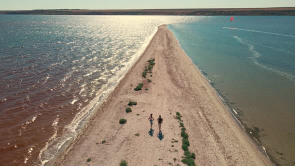 Man and Woman Running By Sand Beach Between Water San Dbar at Mykolaiv Region Ukraine