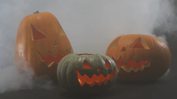 Smoke effect over multiple scary face carved halloween pumpkin against grey background