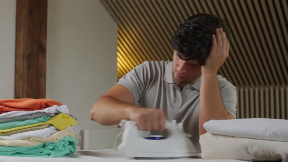 Disgruntled Man with a Stack of Laundry and an Iron